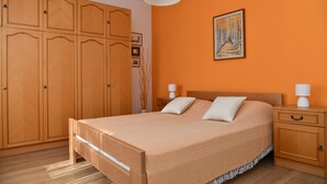 A bedroom with a large bed, wooden wardrobe, and a painting on the wall. - A2 Apartment with terrace, 1 min walking to the beach (Supetar)