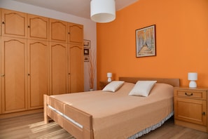 Une chambre avec un grand lit, une armoire en bois et un tableau accroché au mur.