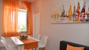 A dining area with a table, chairs, and a painting on the wall. - A2 Apartment with terrace, 1 min walking to the beach (Supetar)