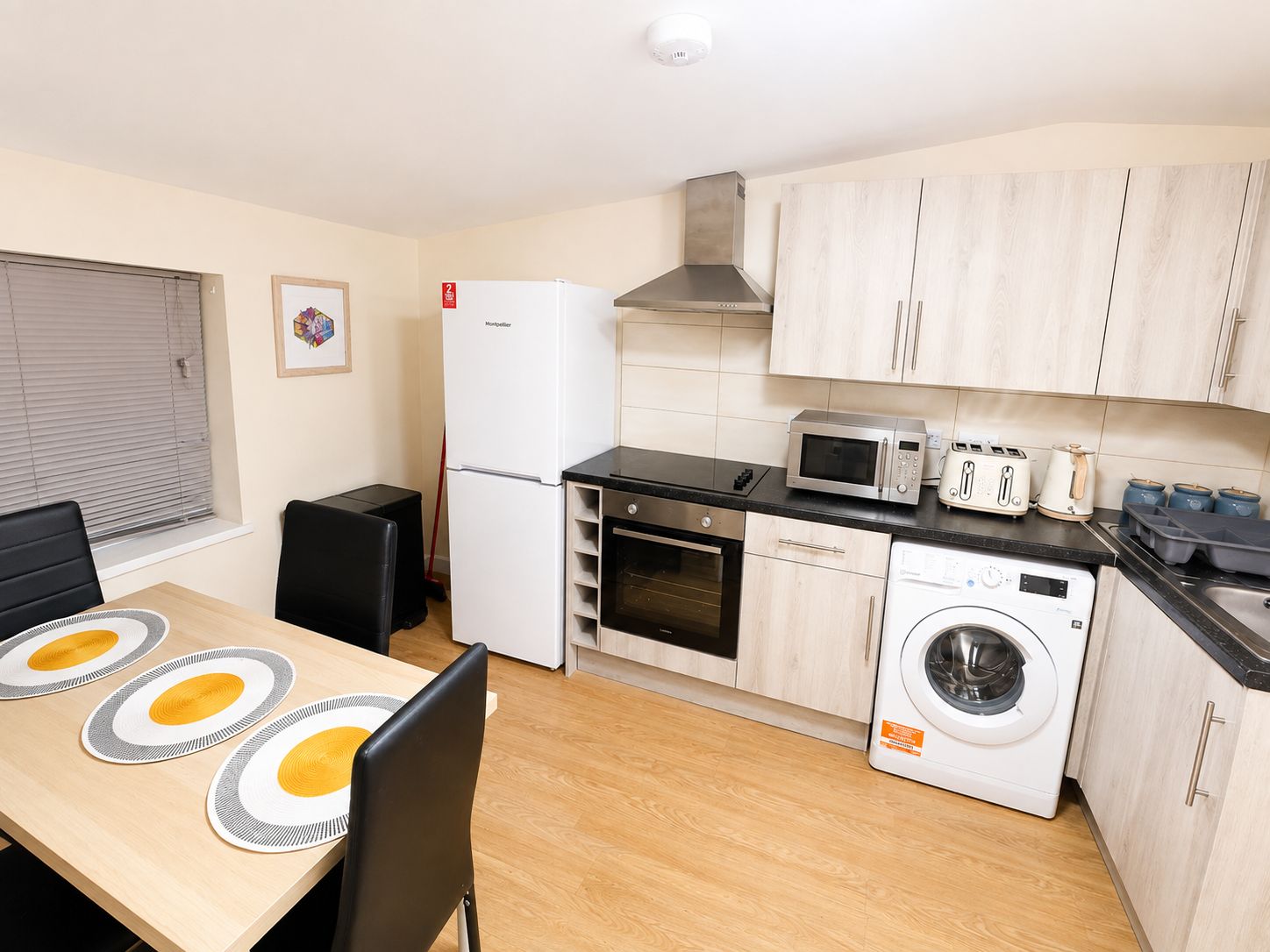 A compact kitchen with a refrigerator, microwave, toaster, and washing machine.