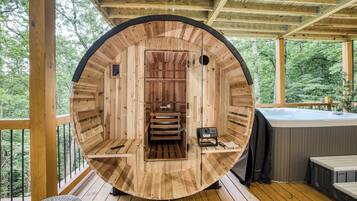 A wooden sauna with a bench, a control panel, and a hot tub outside.
