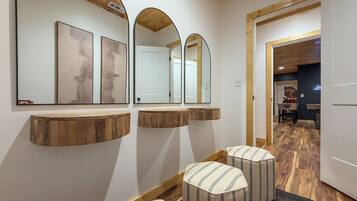 A hallway with wooden beams, a mirror with artwork, and a door leading to a room with a pool table.