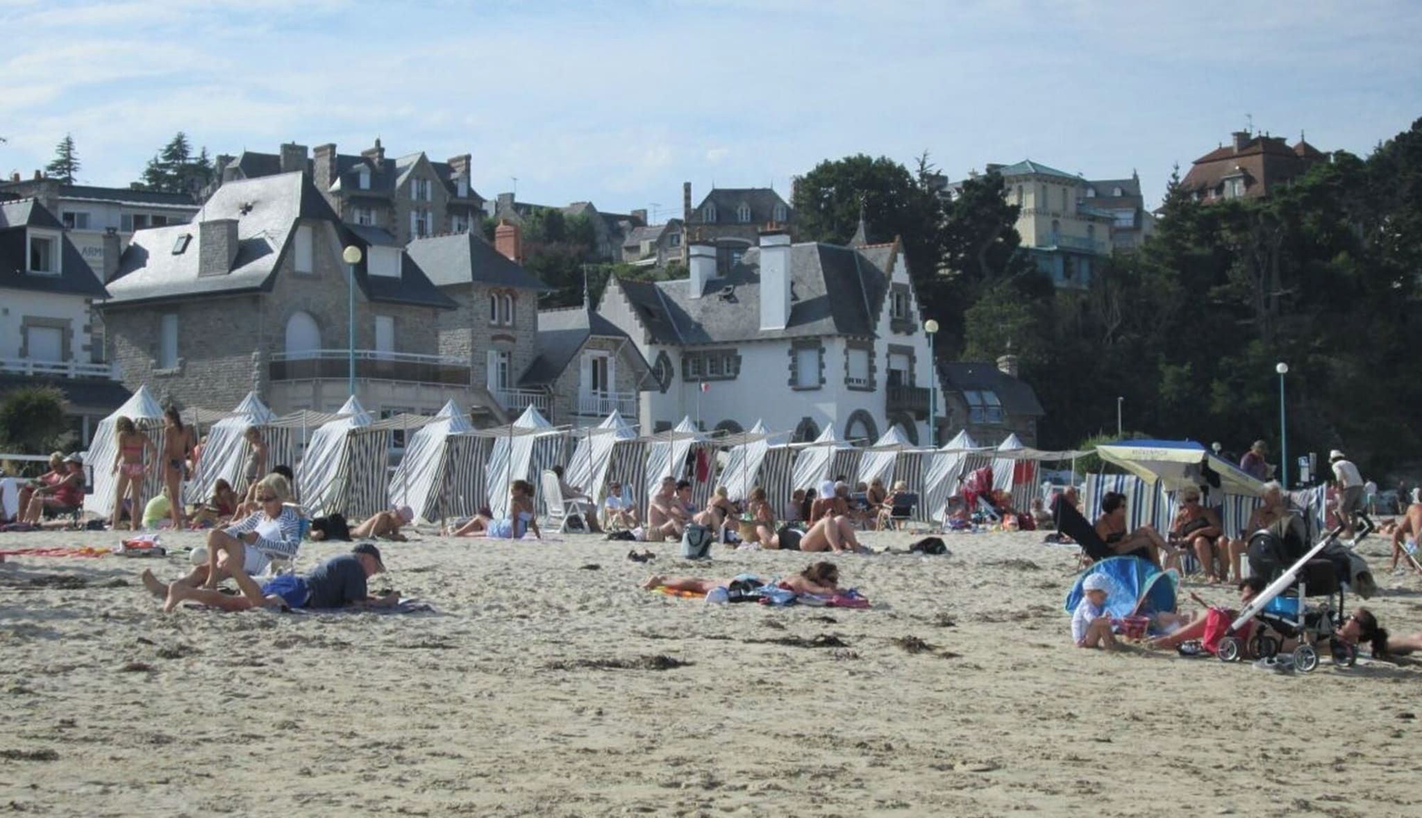 Ein Strand mit Zelten und sonnenbadenden Menschen.