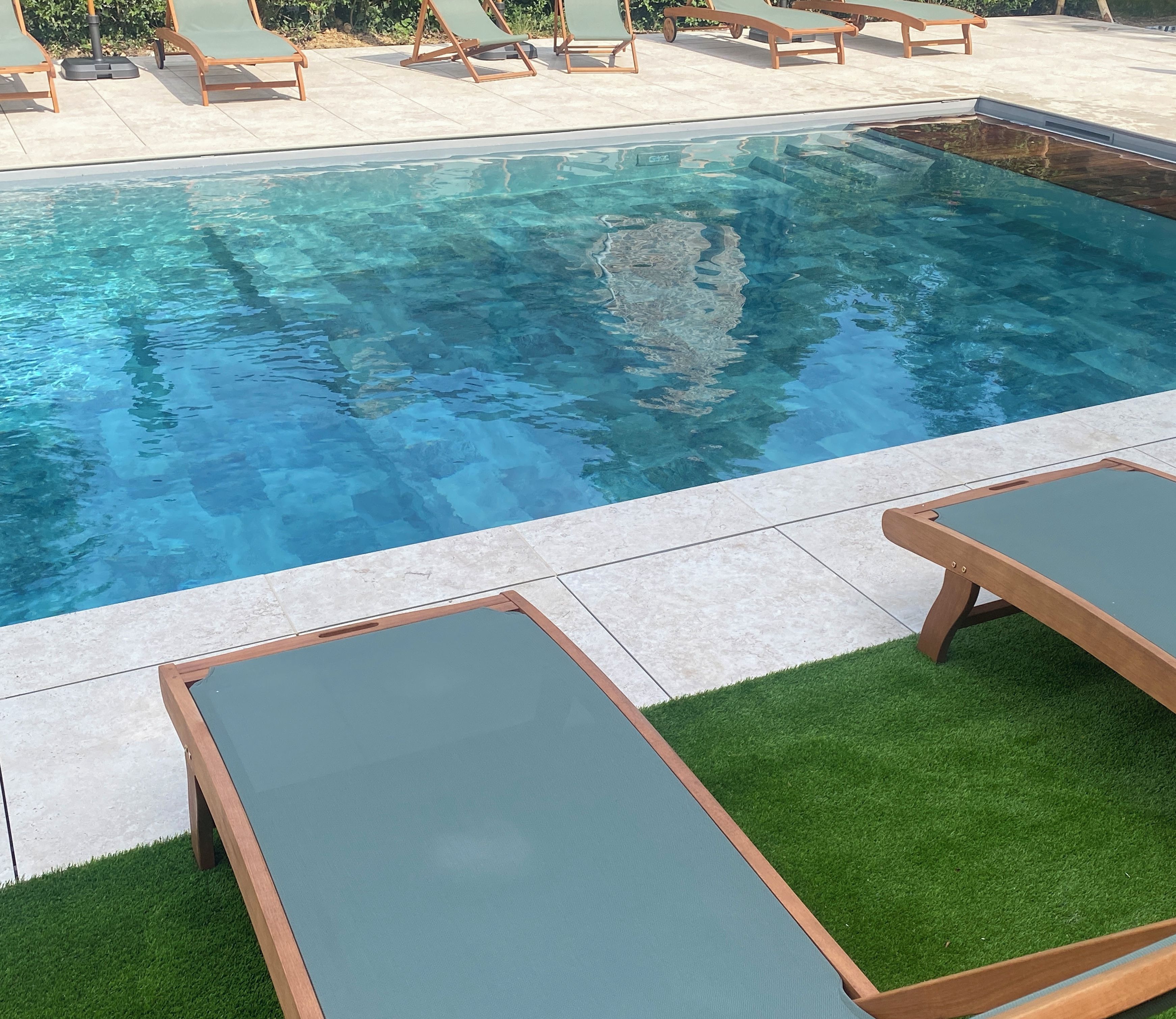 A swimming pool with lounge chairs and artificial grass.