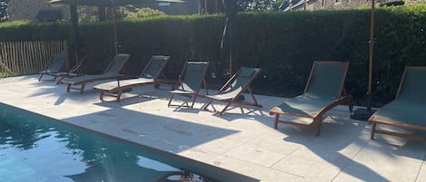 Un espace aménagé au bord de la piscine, avec des chaises longues et des parasols.