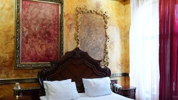 Um quarto luxuoso com uma cama grande, detalhes dourados elaborados, um lustre e uma cortina vermelha.