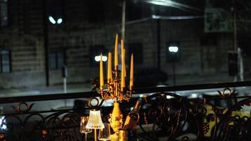 Mesa posta para refeição, com velas, taça de vinho e garrafa.