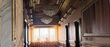 A grand hall with marble columns, a red carpet, and a large chandelier.