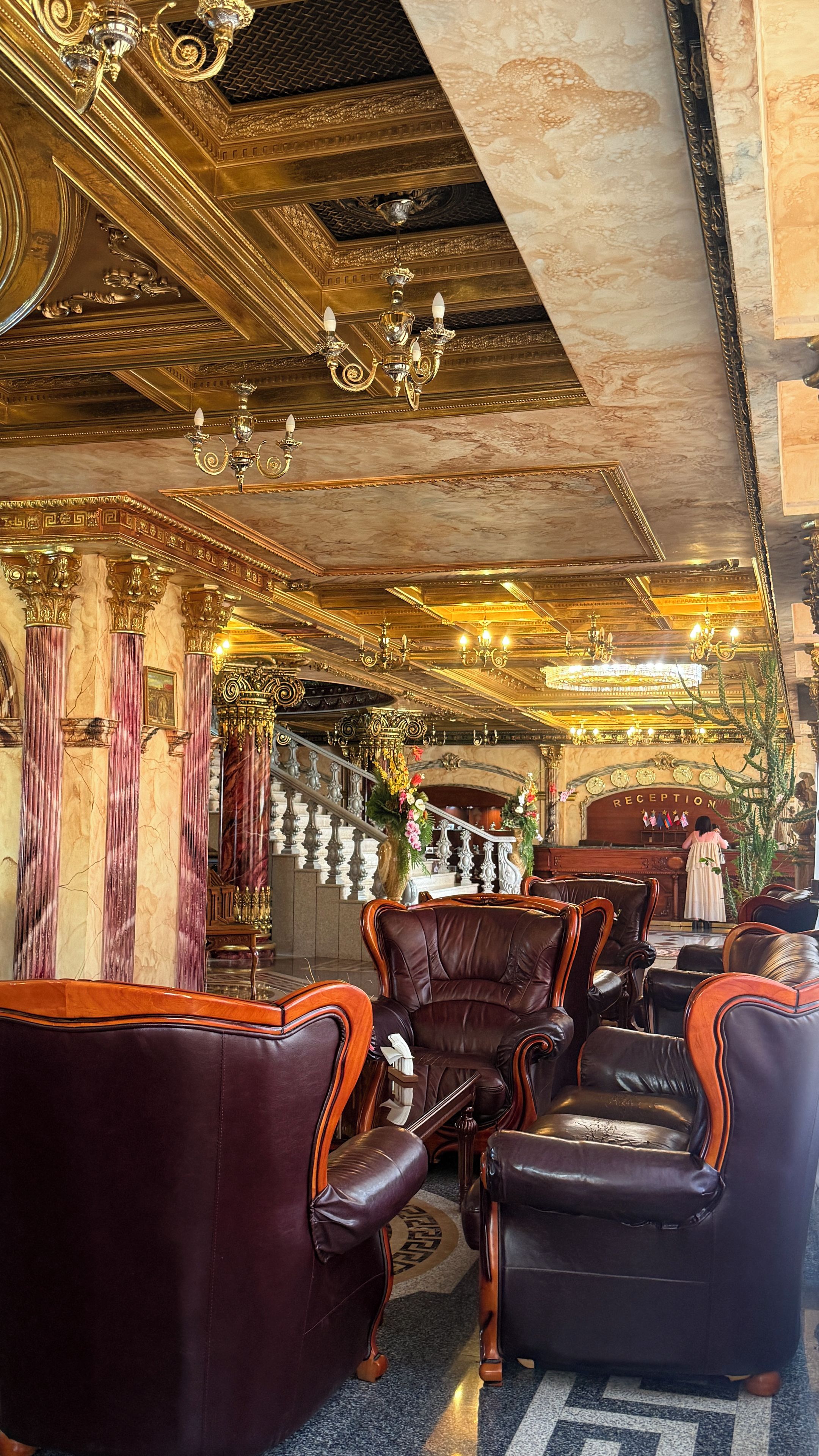 A luxurious interior with ornate chandeliers, marble columns, and leather seating.