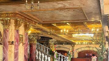 A luxurious interior with ornate chandeliers, marble columns, and leather seating.