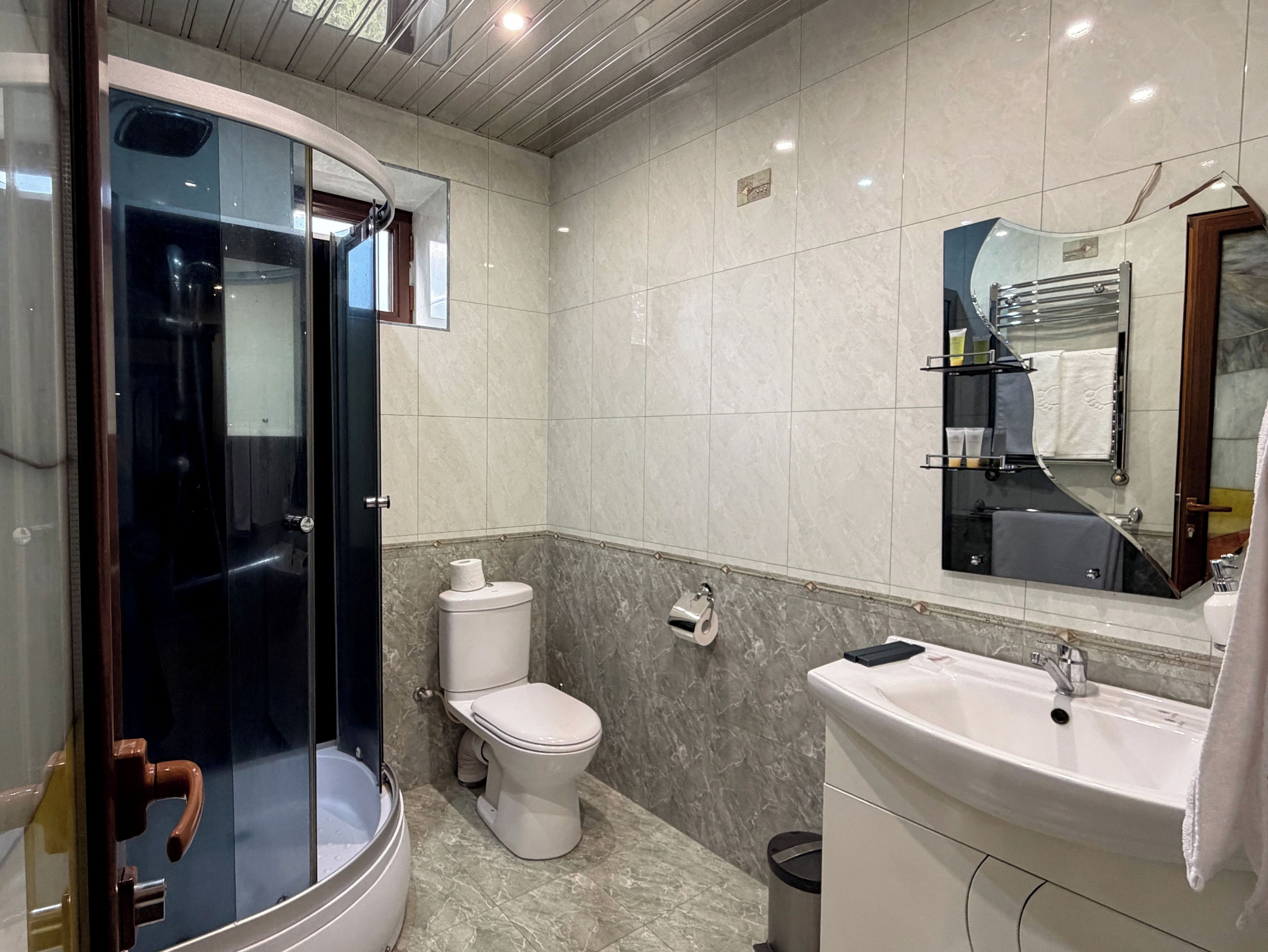 Une salle de bain moderne avec une douche à parois de verre, des toilettes, un lavabo et un miroir.