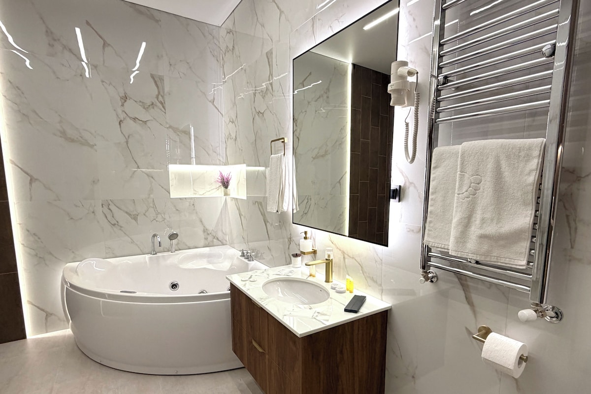 A modern bathroom with a freestanding bathtub, a vanity with a sink, and a large mirror.
