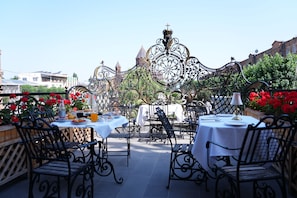 An outdoor dining area with ornate metal railings and tables set for a meal. - Alexandrapol Hotel Palace (Gyumri)
