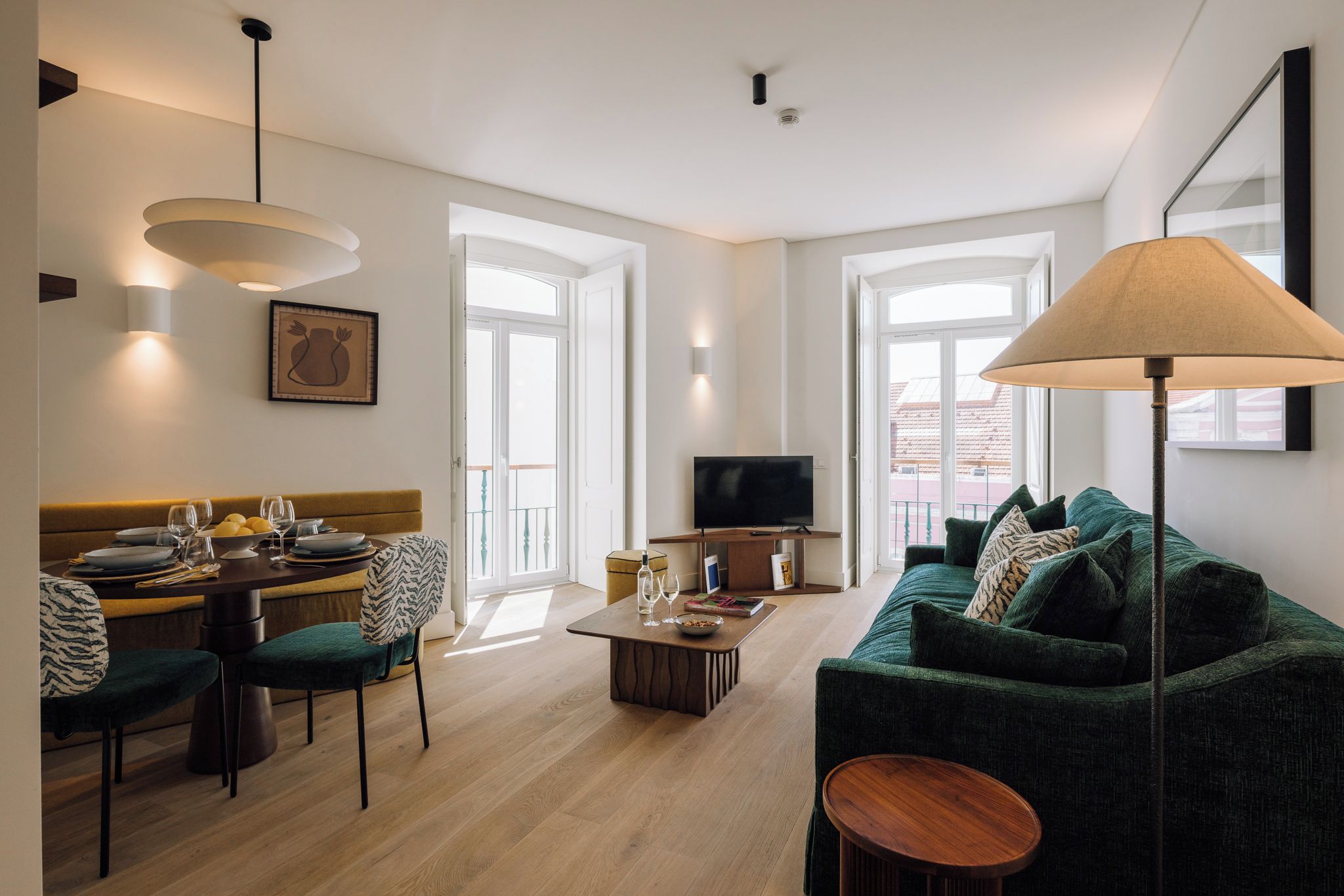A modern living room with a sofa, a dining table, and a TV.