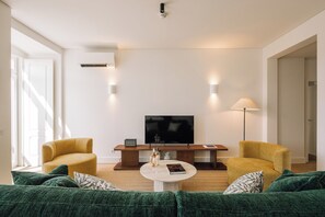 A modern living room with a sofa set, a coffee table, a TV, and two lamps. - Ando Living - Tejo Palace (Lisboa)