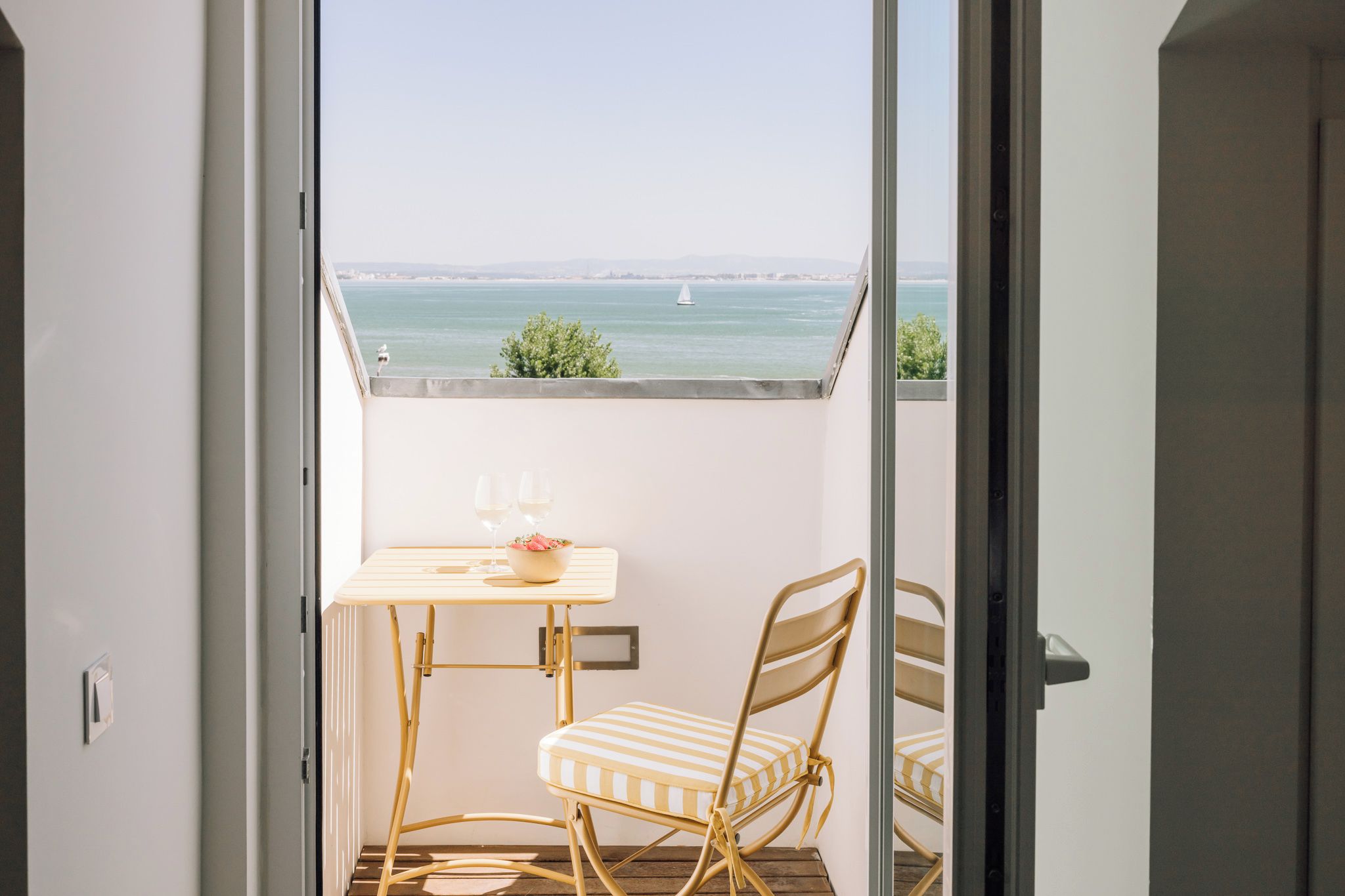 A balcony with a table, two chairs, and a bowl of fruit.