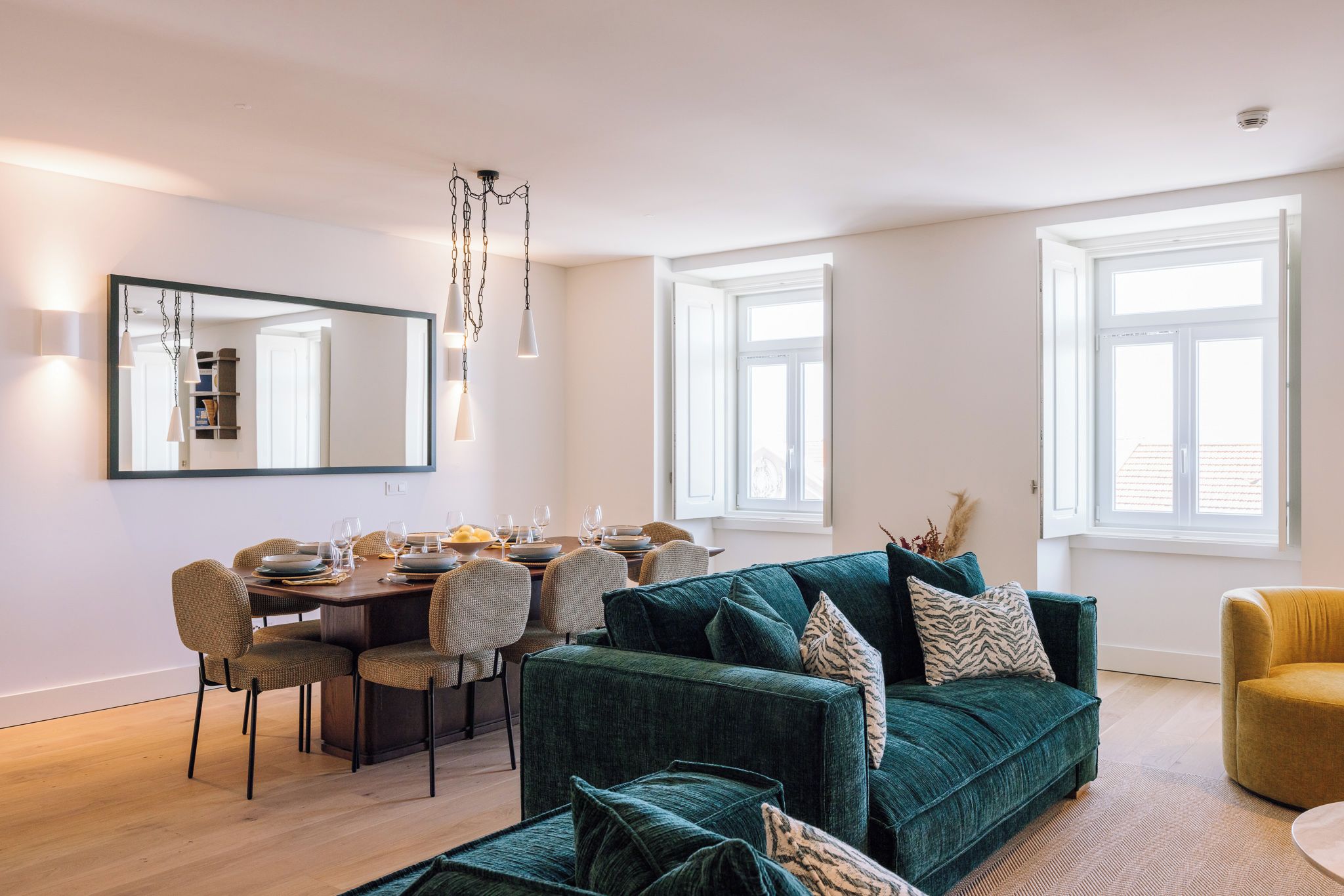 Un salon moderne avec un coin repas, de grandes fenêtres et un lustre.