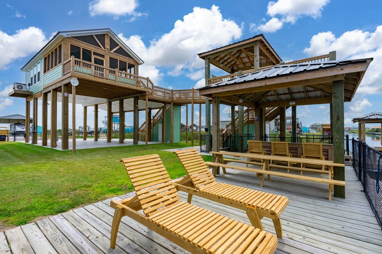 A wooden deck with lounge chairs and a covered seating area, a wooden building with a balcony, and a clear sky.