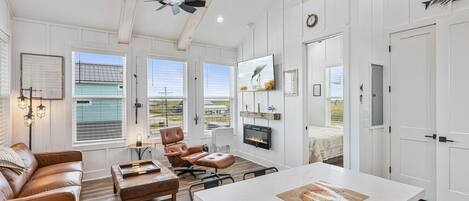 Un salón espacioso con un gran ventanal, chimenea y ventilador de techo.