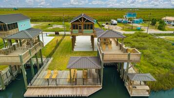 A waterfront property with multiple docked structures, a central building with a covered deck, and a surrounding grassy landscape.