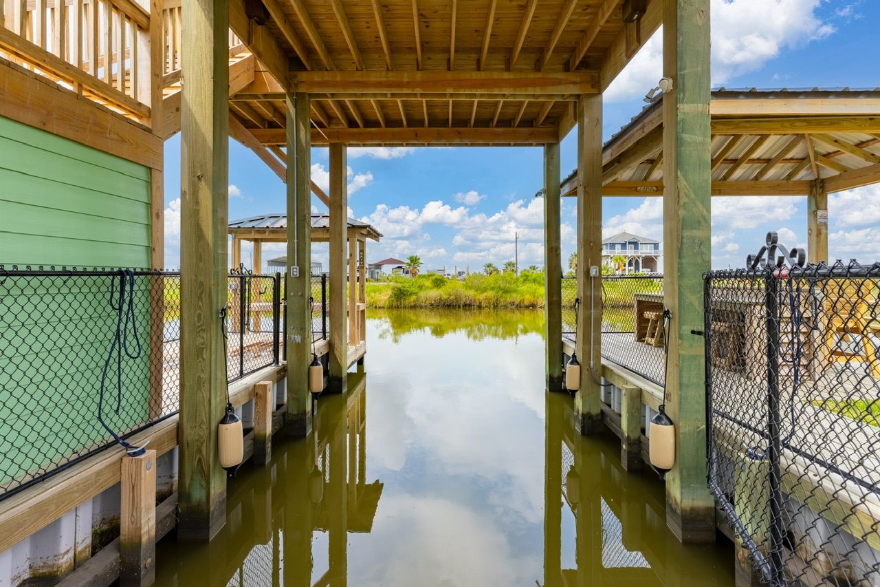 A covered wooden structure with a water body in front, surrounded by a fence.