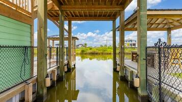 A covered wooden structure with a water body in front, surrounded by a fence.