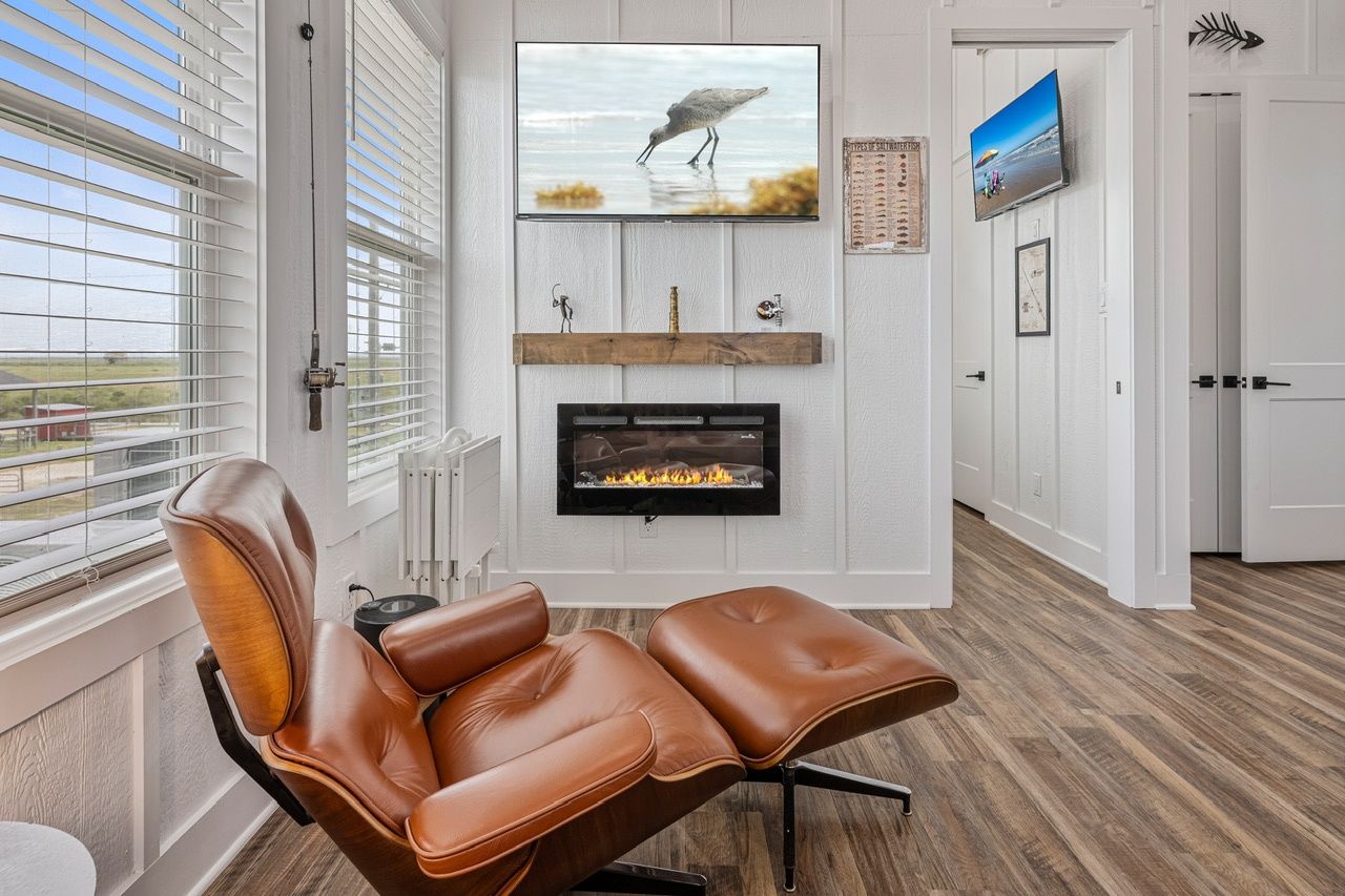 A modern living room with a leather recliner, a fireplace, and a television mounted on the wall.