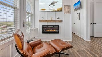 A modern living room with a leather recliner, a fireplace, and a television mounted on the wall.