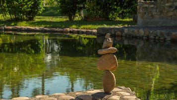 Ein ruhiger Teich, im Vordergrund ein Steinstapel und im Hintergrund eine Steinmauer.