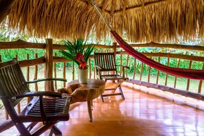 Un espacio al aire libre con mobiliario de madera, una mesa y una hamaca.
