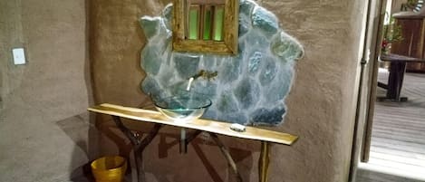 A bathroom with a stone sink, a mirror, and a wooden vanity.
