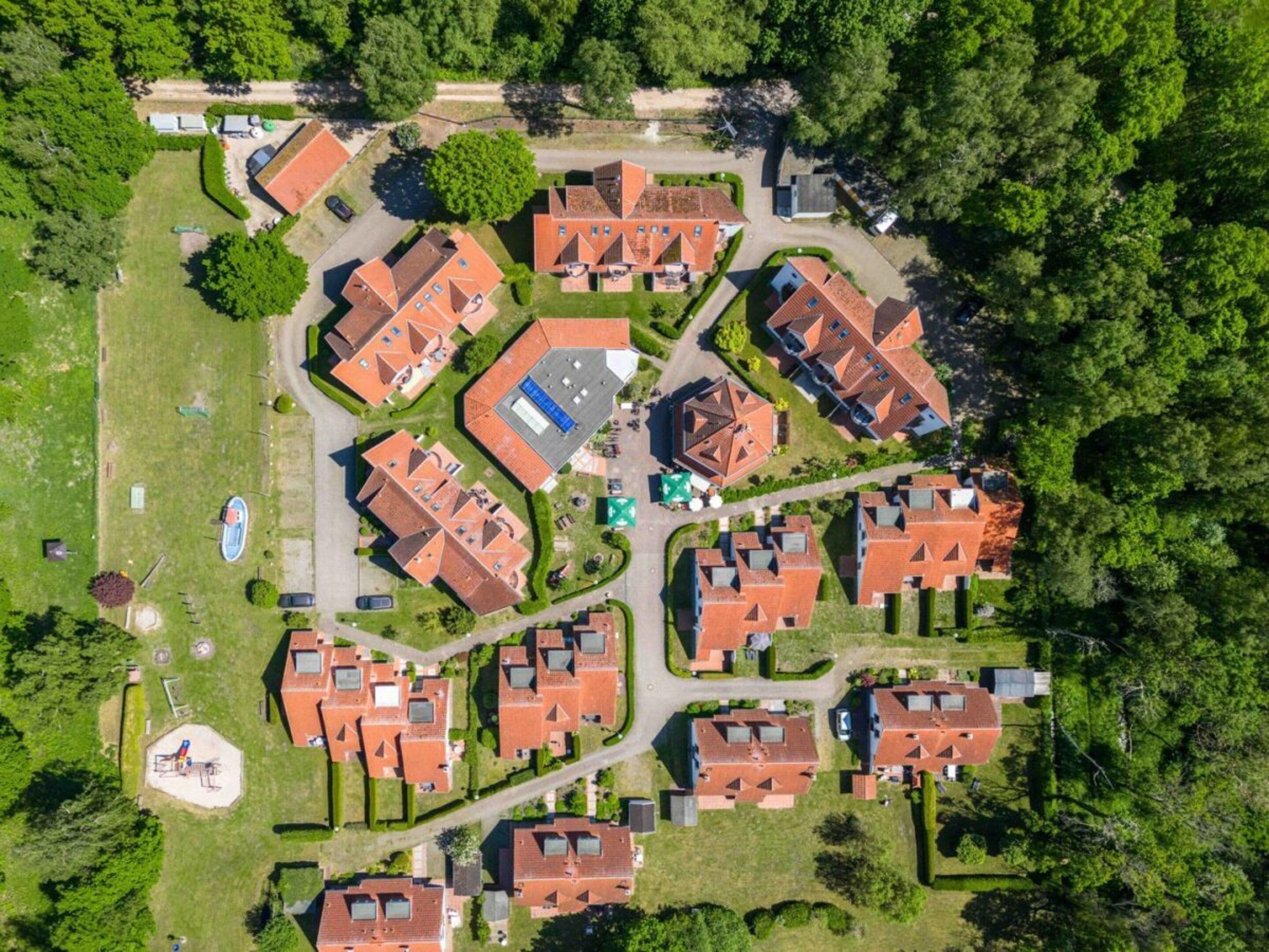 Ein Luftbild eines Wohngebiets mit mehreren Häusern, einem Spielplatz und einem Sportplatz.