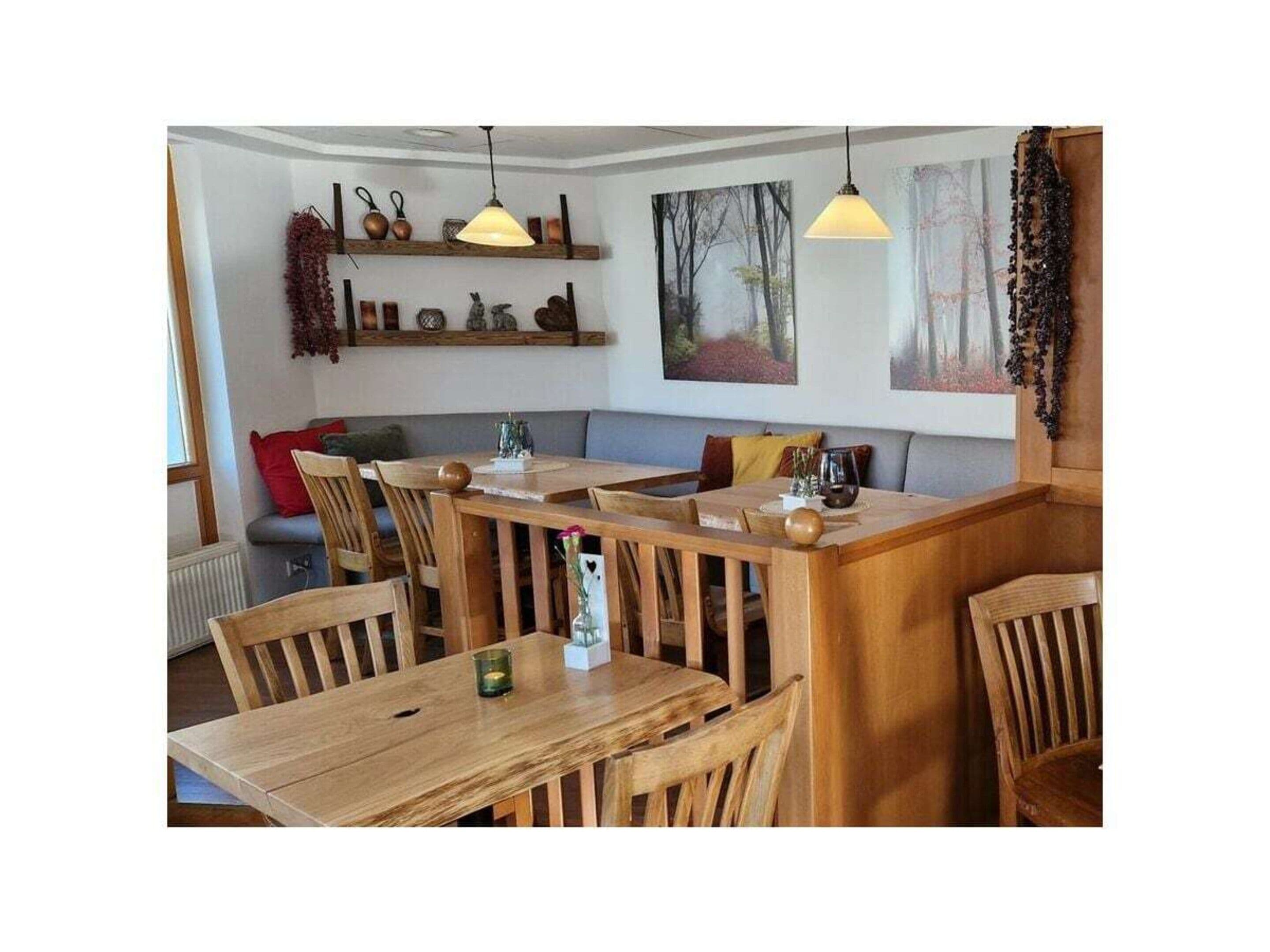 Een gezellig restaurant met houten tafels en stoelen, hanglampen en kunstwerken aan de muren.
