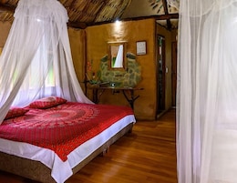 A room with a bed, a table with a mirror, and a stone wall.