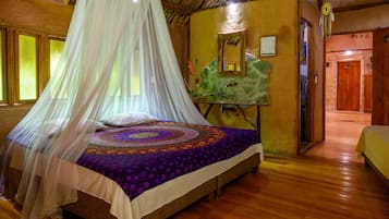 A room with a bed under a canopy, a stone wall, and a wooden door.
