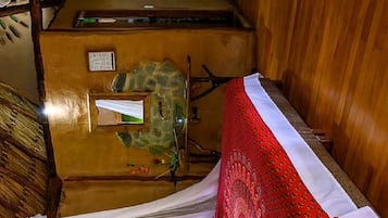 A room with a bed under a canopy, a wooden desk, and a stone wall.