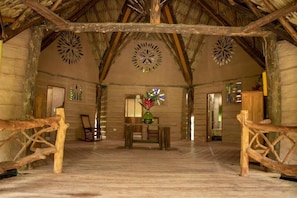 A rustic interior with a wooden floor, a central table with chairs, and decorative wall art.