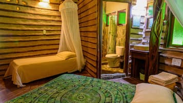 A room with a bed, a small table, a toilet, and a shower area.