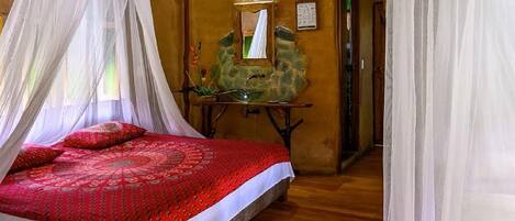 Una habitación con una cama, una mesa con espejo y una pared de piedra.