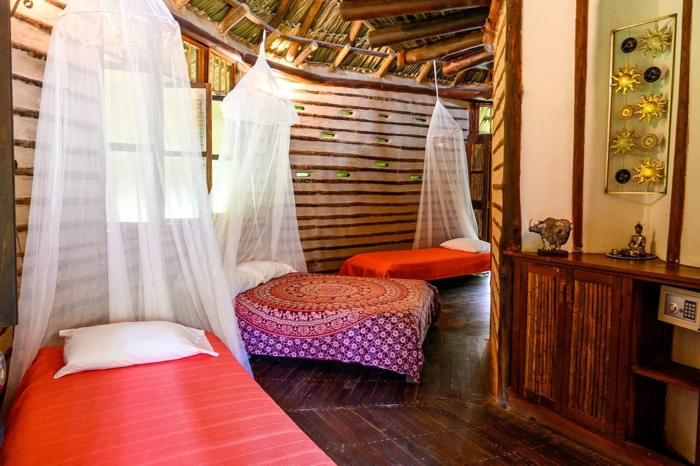 A room with two beds, each with a canopy, a small table with decorative items, and a wooden ceiling.