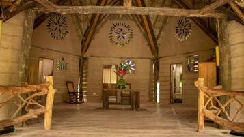 A rustic interior with a wooden floor, a central table with chairs, and decorative wall art.