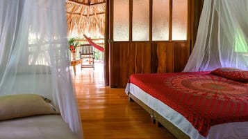 Een kamer met een bed, een stoel en een rieten dakconstructie.