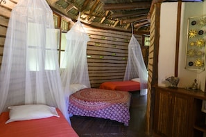 Habitación con dos camas, cada una con dosel, una mesita con adornos y una pared con un diseño original.