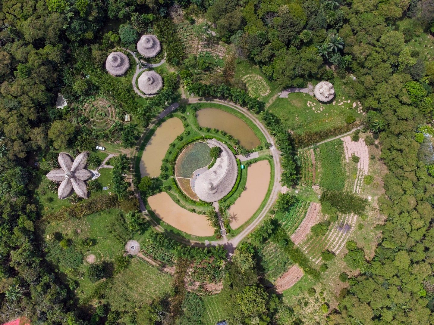 Vue aérienne d’un parc avec des bassins circulaires, une grande structure en forme de fleur et plusieurs bâtiments ronds.