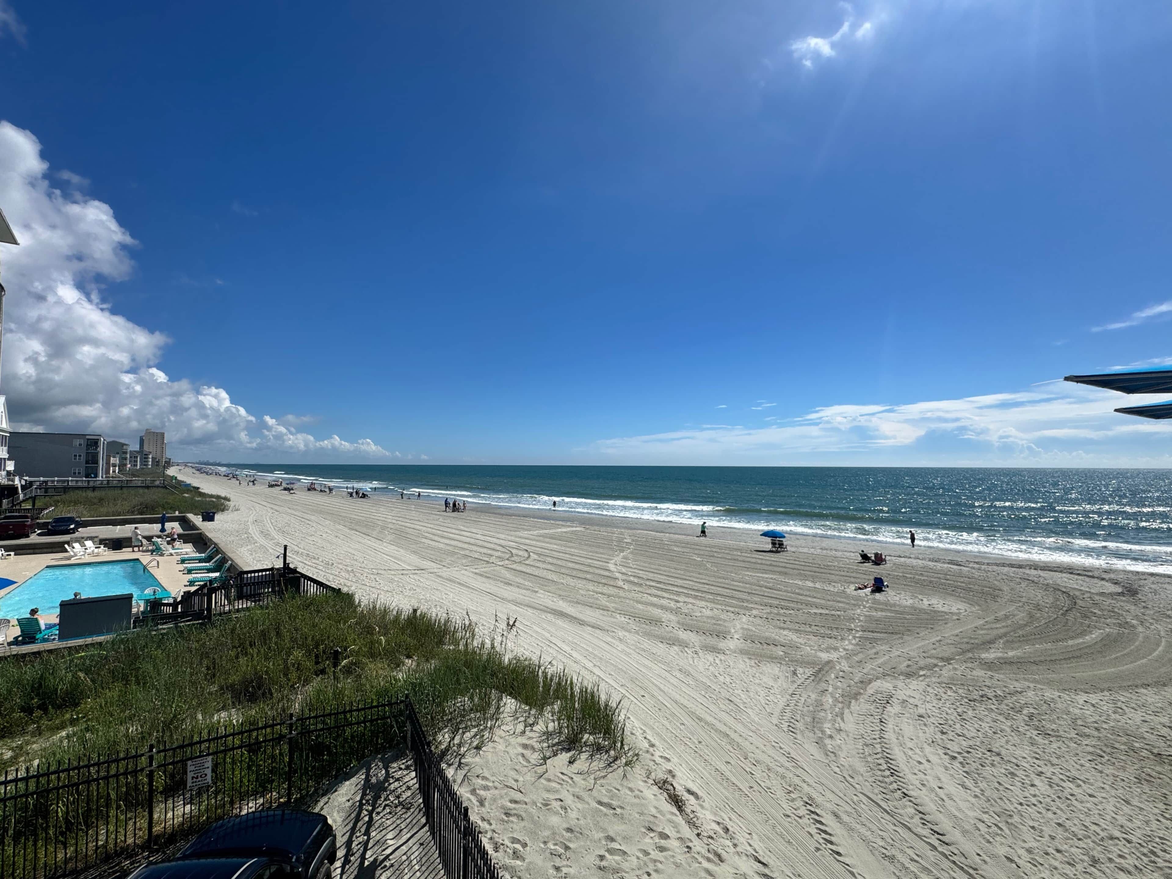 Ein Strand mit Schwimmbad, Zaun und blauem Himmel.