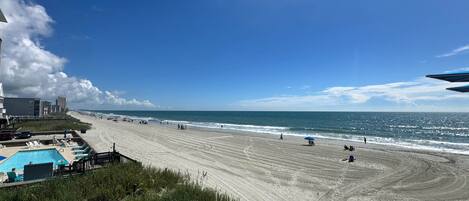 Ein Strand mit Schwimmbad, Zaun und blauem Himmel.