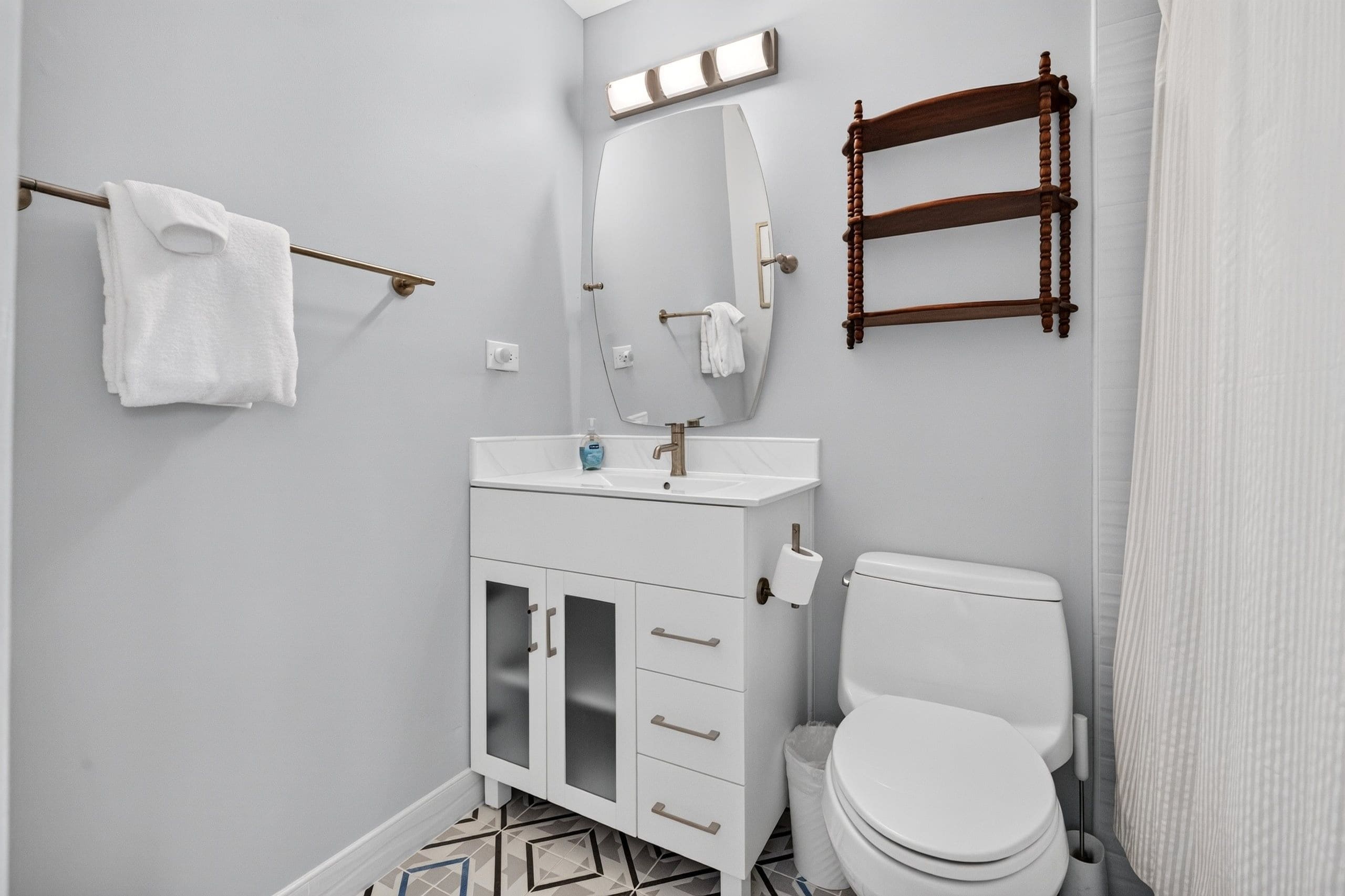 Une salle de bain avec des toilettes blanches, un lavabo avec un miroir au-dessus et un porte-serviettes avec une serviette.
