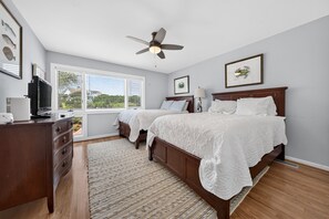 A bedroom with two beds, a ceiling fan, a TV, and artwork on the walls. - A Place To Land 3 Bedroom Villa (Georgetown)