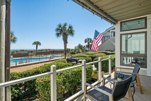 A pool area with a view of the ocean, a flag, and outdoor furniture. - A Place To Land 3 Bedroom Villa (Georgetown)