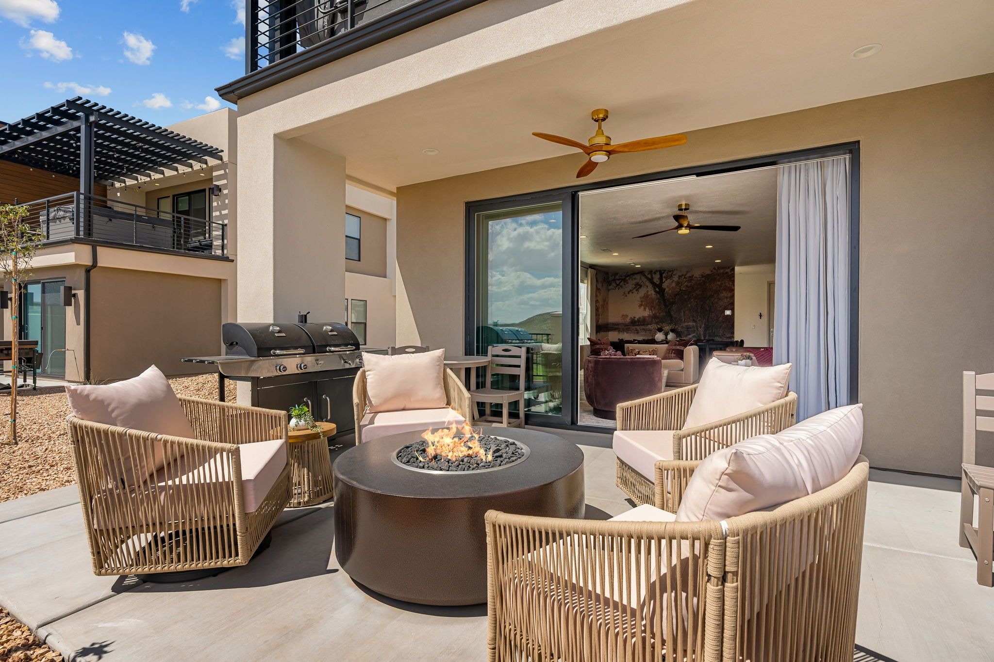Une terrasse extérieure aménagée avec des meubles en osier, un foyer et un barbecue.